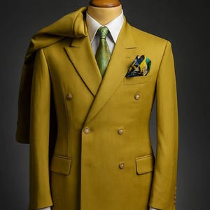 May include: A mustard-colored double-breasted suit with a matching overcoat draped over the shoulders. The suit features a white dress shirt, a patterned green tie, and a pocket square. The text "HUSSAINBYANAS" is at the top.