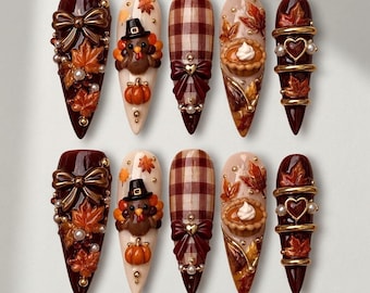 May include: A set of ten press-on nails featuring autumn themes. Designs include dark red nails with 3D bows and leaves, cream nails with a turkey and pumpkin, brown plaid patterns with bows, cream nails with a pie, and dark red nails with gold rings.