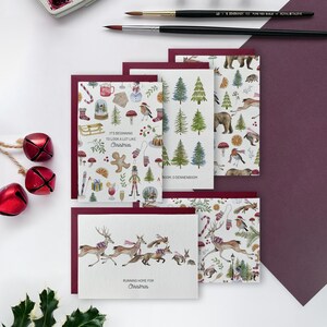 Op de afbeelding: Een verzameling kerstkaarten met feestelijke illustraties. De kaarten tonen afbeeldingen van peperkoekenmannen, rendieren en kerstbomen. De tekst op de kaarten luidt "It's beginning to look a lot like Christmas" en "Running home for Christmas."