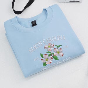 Embroidered Dogwood flower on light blue sweatshirt