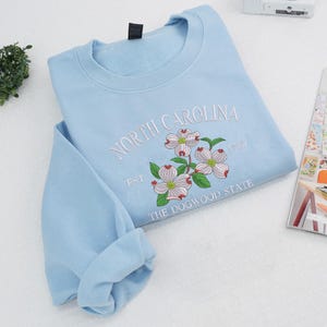Embroidered Dogwood flower on light blue sweatshirt