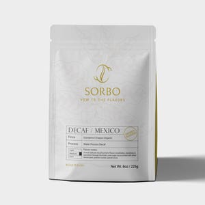 Könnte beinhalten: Weißer Kaffeepackung mit dem Text "SORBO" und "VOW TO THE FLAVORS". Die Packung ist mit "DECAF / MEXICO" und "Net Wt. 225g" beschriftet. Auf der Packung steht auch "FRESHLY ROASTED".