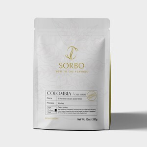 May include: A white coffee bag with the brand name "SORBO" and the text "VOW TO THE FLAVORS". The bag is labeled "COLOMBIA / CAFE URIBE" and "FRESHLY ROASTED". It contains 10oz / 285g of coffee.