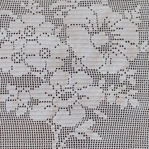 May include: A white rectangular crochet doily featuring a detailed floral pattern created with a grid-like mesh stitch. The edges are finished with a scalloped border, and the central design displays intricate flower blossoms and leaves.