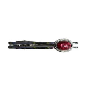 May include: A silver-toned tie clip with a red oval-shaped stone. The stone is surrounded by a rope-like border. The clip is designed to hold a tie in place, adding a touch of elegance to formal wear.
