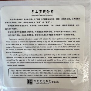 May include: A white paper with Chinese text and English translation about handmade paper-cut art. The text describes the history, techniques, and cultural significance of paper-cut art, including its use in window decorations.