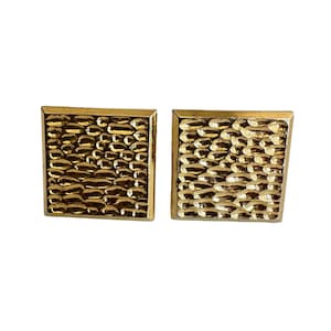 May include: A pair of gold-toned square cufflinks. Each cufflink features a textured, hammered design within a square frame. The surface has a pattern of irregular, rounded shapes, creating a unique, eye-catching accessory.