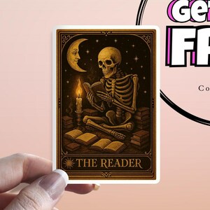 May include: A sticker featuring a skeleton reading a book by candlelight under a crescent moon and stars. The sticker has a gold border and the words "THE READER" at the bottom. The overall theme is tarot and the occult.