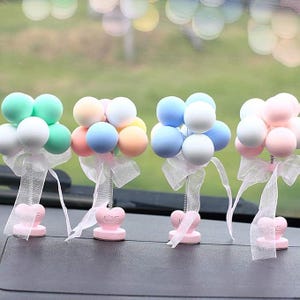May include: Four decorative ornaments featuring clusters of pastel-coloured spheres arranged like balloons. Each cluster sits atop a thin metal spring attached to a small pink heart-shaped base with the word LOVE, accented by a white sheer ribbon.