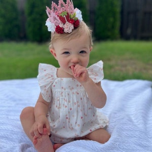 Pink lace strawberry first birthday crown with red and blush flowers, glittery strawberry topper, and number one detail. Perfect for a Sweet One birthday, berry first birthday, cake smash photoshoot, or toddler party hat. Handmade and customizable.