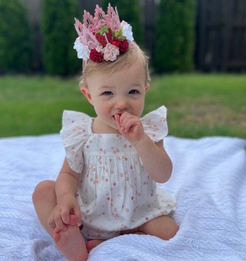 Pink lace strawberry first birthday crown with red and blush flowers, glittery strawberry topper, and number one detail. Perfect for a Sweet One birthday, berry first birthday, cake smash photoshoot, or toddler party hat. Handmade and customizable.
