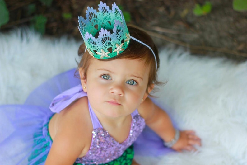 Mermaid first birthday crown with aqua lace, gold glitter starfish, and a glittery “one” topper. Perfect for a mermaid birthday party, Oneder the Sea theme, cake smash photoshoot, or beach baby shower. Handmade, lightweight, and customizable.