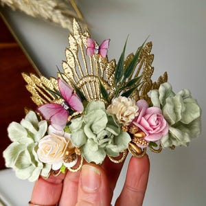 Gold lace tiara adorned with sage green, soft pink, and ivory faux flowers, delicate organza butterflies, and golden leaves. Perfect for baby girl or toddler girl fairy-themed birthdays, photoshoots, or special occasions. Handcrafted with attention to detail for a whimsical and elegant boho look.