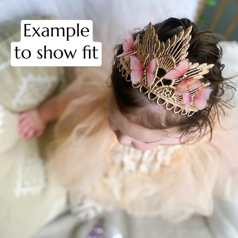 May include: Gold crown headband with pink butterfly embellishments. The crown is made of delicate lace and features a delicate floral design.