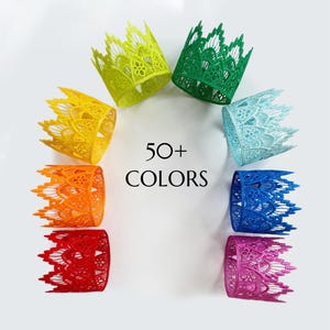 May include: A collection of colorful lace crowns arranged in a circle. The crowns are in various colors, including yellow, green, blue, and pink. The text "50+ COLORS" is in the center. These crowns are likely for parties or crafts.