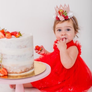 Pink lace strawberry first birthday crown with red and blush flowers, glittery strawberry topper, and number one detail. Perfect for a Sweet One birthday, berry first birthday, cake smash photoshoot, or toddler party hat. Handmade and customizable.