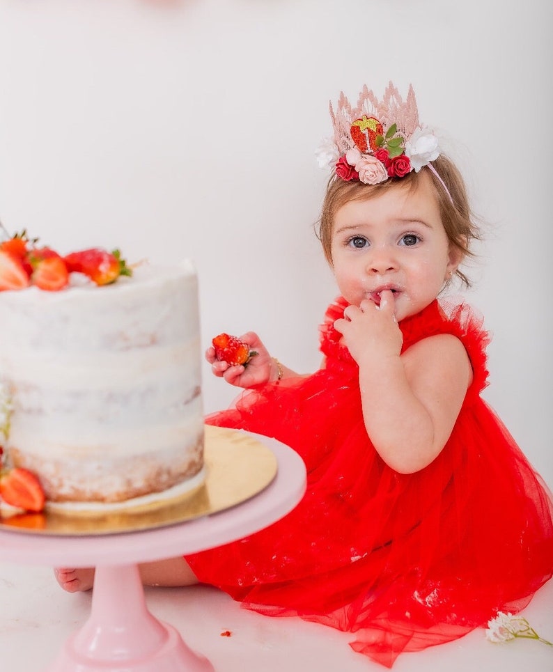 Pink lace strawberry first birthday crown with red and blush flowers, glittery strawberry topper, and number one detail. Perfect for a Sweet One birthday, berry first birthday, cake smash photoshoot, or toddler party hat. Handmade and customizable.