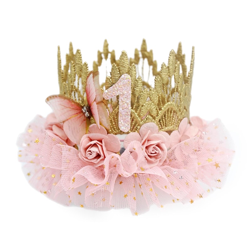 Gold lace crown with sparkly blush number 1, organza butterfly with rhinestone detail, blush pink roses, and blush pink ruffled tutu trim with gold stars. Perfect for baby girl first birthday, cake smash photoshoot, and fairy princess theme. Handmade by LoveCrush Crowns®. Can be customized in any age.