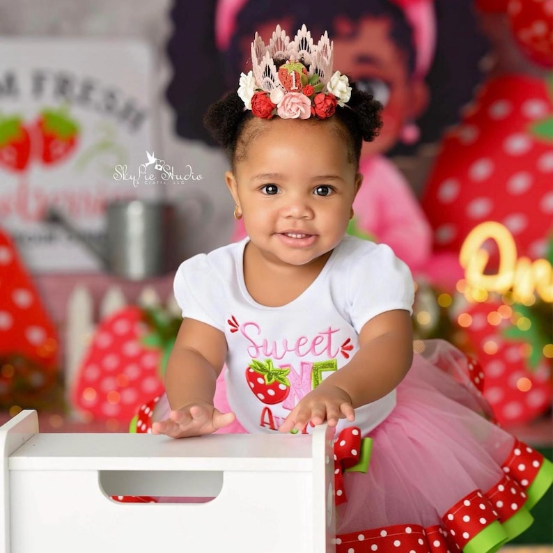 Pink lace strawberry first birthday crown with red and blush flowers, glittery strawberry topper, and number one detail. Perfect for a Sweet One birthday, berry first birthday, cake smash photoshoot, or toddler party hat. Handmade and customizable.