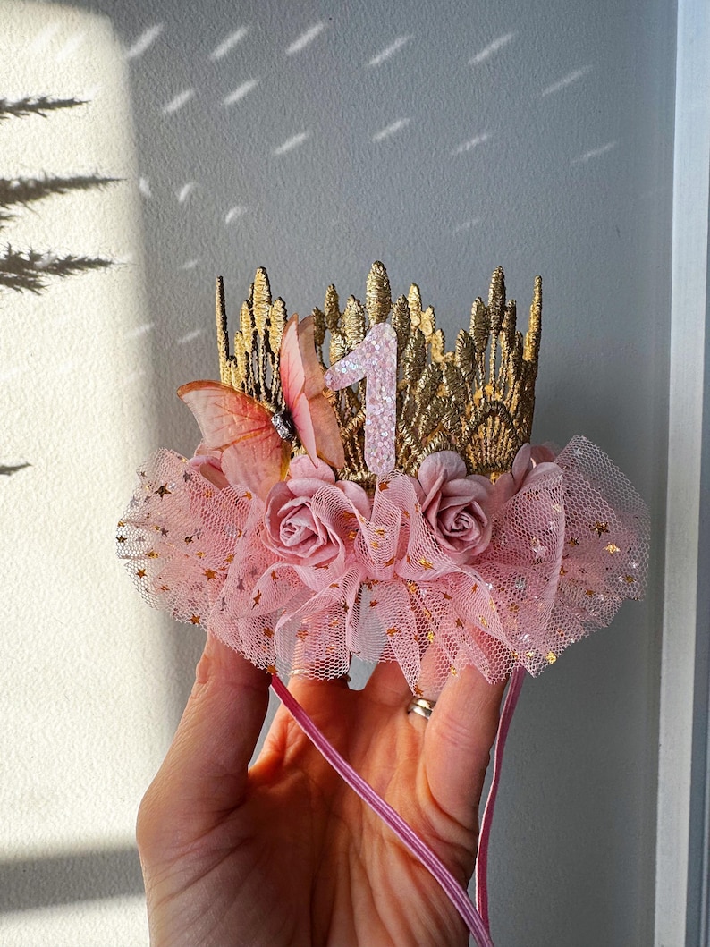 Blush pink fairy tutu crown with lace details, golden stars, and handcrafted floral embellishments. A perfect baby girl birthday headband for princess dress-up, cake smash, and first birthday celebrations. LoveCrush Crowns® specializes in unique handmade crowns made in the USA.