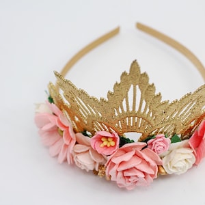 May include: Gold crown headband with pink and white felt flowers. The crown is made of a delicate lace design.
