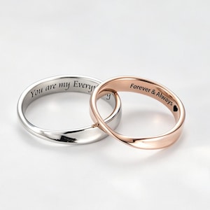 May include: Two intertwined rings, one silver and one rose gold, against a white background. The silver ring has the inscription "You are my Every" and the rose gold ring reads "Forever & Always". The rings are a symbol of love and commitment.