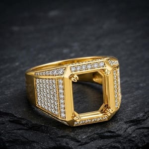 Puede incluir: Un engaste de anillo en tono dorado con un soporte central rectangular de cuatro garras, diseñado para sostener una piedra preciosa. La banda y el marco rectangular están incrustados con numerosas piedras pequeñas, claras y de corte redondo.