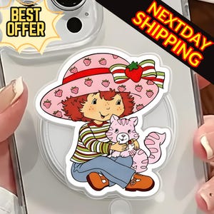 May include: A colorful sticker featuring a cartoon character wearing a pink hat with strawberry designs, holding a pink cat. The character is wearing a striped shirt and blue pants. The sticker has the text "BEST OFFER" and "NEXTDAY SHIPPING".