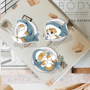 May include: A set of three ceramic mugs with a speckled, matte finish. The mugs are in shades of cream, light gray, and dark gray. Each mug has a simple, minimalist design, perfect for coffee or tea.