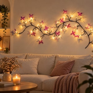 Puede incluir: Un aplique de pared decorativo con una estructura de rama oscura, adornado con numerosos pequeños adornos de mariposas translúcidas de color rosa y morado, cada uno iluminado por una luz LED blanca cálida integrada en el diseño.