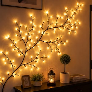 Könnte beinhalten: Eine wandmontierte, dekorative Ast-Lichterkette mit dunkelbraunen Zweigen, die mit zahlreichen kleinen, warmweiß leuchtenden LED-Lichtern bestückt ist. Der Ast erstreckt sich horizontal an der Wand und bildet eine baumartige Silhouette.