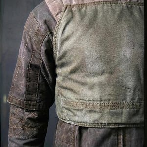 Puede incluir: Chaqueta desgastada en verde oliva y marr&oacute;n con detalles acolchados. La chaqueta tiene cuello alto y hombros acolchados. Las mangas tienen un dise&ntilde;o en capas. La prenda se exhibe en un maniqu&iacute;.