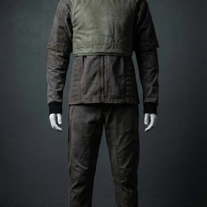 Puede incluir: Toma de cuerpo entero de un maniqu&iacute; con un conjunto de dos piezas. El conjunto consta de una chaqueta con un panel verde en el pecho y pantalones a juego. La chaqueta tiene mangas largas y cuello alto. Los pantalones tienen un dise&ntilde;o de pierna recta. El conjunto es de color marr&oacute;n apagado.