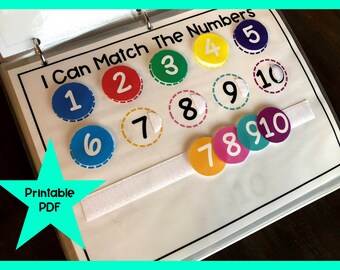 May include: A printable PDF activity for kids to learn numbers. The activity features a white binder with colorful circles with numbers 1 through 10. The circles are attached to a white strip of velcro.