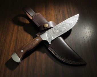 May include: A Damascus steel hunting knife with a wooden handle and a brown leather sheath. The blade has a unique swirling pattern. The knife is resting on a dark wooden surface.