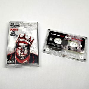 May include: A white ceramic mug with a black handle and the text "But First, Coffee" in a black, handwritten-style font. The mug is on a white surface.