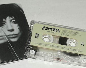 May include: A clear cassette tape labelled "MAYHEM LVDY GAGA" with a tracklist including "Disease" and "Celebrity." Next to it is a black and white image of a person.