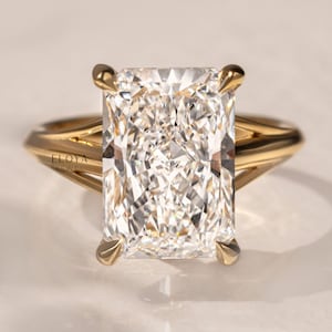 Peut inclure: Bague en or avec un diamant taille radiant rectangulaire. Le diamant est serti de quatre griffes. La monture présente un design à tige fendue. La bague est un bijou.