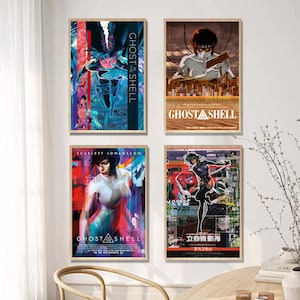 May include: Four framed posters featuring artwork from the anime film "Ghost in the Shell." The posters showcase different character illustrations and movie titles. The color palette includes blues, reds, and browns. The posters are displayed on a wall.