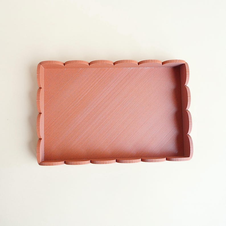 Puede incluir: Una bandeja rectangular de madera de color coral con borde festoneado. La bandeja tiene un dise&ntilde;o sencillo y limpio y una superficie ligeramente texturizada. La bandeja est&aacute; vac&iacute;a y se encuentra sobre un fondo neutro.