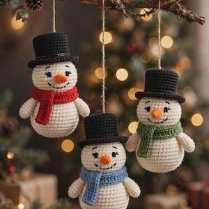 May include: Three crocheted snowman ornaments hanging from a branch. Each snowman is off-white with a black top hat, an orange carrot nose, and a scarf in either red, green, or blue. They feature embroidered black eyes and mouths.