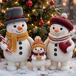 May include: Three crocheted snowmen figures standing together. The largest wears a grey top hat and yellow scarf, holding a candy cane. The medium one wears a maroon beret and scarf, holding a red heart. The smallest wears a yellow hat.