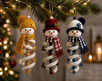 May include: Three crocheted snowman ornaments hanging from a branch. The left snowman wears a mustard yellow hat and scarf with yellow stars. The centre snowman has a red top hat and scarf with holly. The right snowman has a navy blue hat and scarf with blue snowflakes.