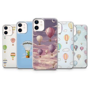 May include: A selection of phone cases with hot air balloon illustrations. The cases showcase colourful balloons against cloud, sky, and night scenes with a crescent moon. The cases are made of clear plastic.