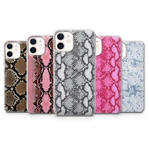 May include: A collection of five phone cases with snake skin patterns. The cases feature a variety of colors, including brown, pink, gray, and blue. Each case has a clear border and a camera cutout.