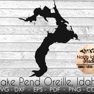 May include: Black silhouette of Lake Pend Oreille, Idaho, on a white woodgrain background. The text "North Idaho Made" is on a woodgrain circle with mountains in the background. The text "SMALL LOCAL FAMILY" is below the circle. The text "Lake Pend Oreille, Idaho" is below the image. The text "SVG - DXF - EPS - PDF - PNG - CDR" is below the lake.