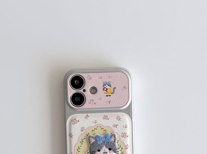 a smartphone with a pink and white floral case and a cat design on the back cover.