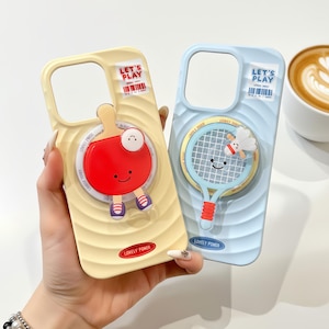 Könnte beinhalten: Zwei Handyhüllen, eine gelbe und eine blaue, jeweils mit Sportmotiven. Die gelbe Hülle hat ein rotes Tischtennisschläger-Design, während die blaue Hülle einen Badminton-Schläger zeigt. Beide Hüllen haben den Text "LET'S PLAY".