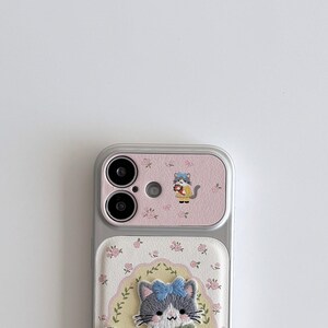 a smartphone with a pink and white floral case and a cat design on the back cover.