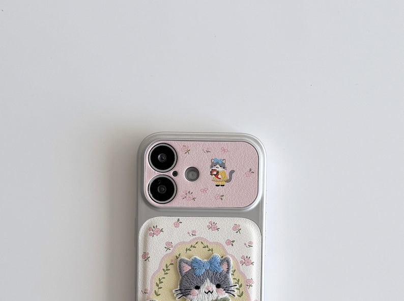 a smartphone with a pink and white floral case and a cat design on the back cover.